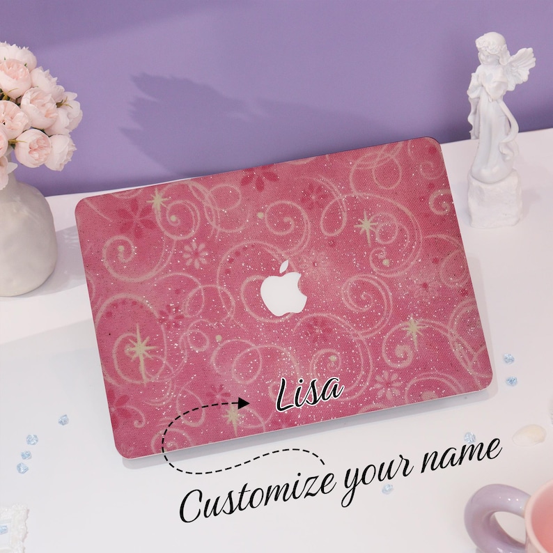 May include: Pink laptop cover with a floral and swirl design, featuring the Apple logo. The cover is personalised with the name "Lisa" and the text "Customize your name".