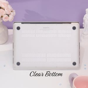 May include: The bottom of a white laptop with a clear case. The case has a "MacBook Pro" logo and a clear bottom. The text "Clear Bottom" is written below the laptop.
