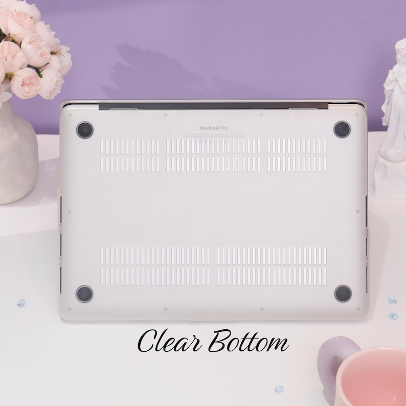 May include: The bottom of a white laptop with a clear case. The case has a "MacBook Pro" logo and a clear bottom. The text "Clear Bottom" is written below the laptop.