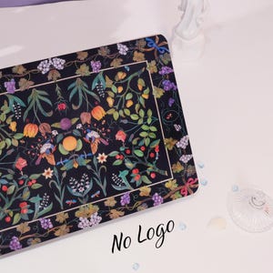 May include: A black rectangular placemat with a colorful floral design featuring birds, grapes, and flowers. The design is framed by a black border with a grapevine pattern.