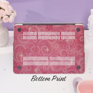 May include: A pink laptop case featuring a floral and swirl pattern. The case has white ventilation slots and black rubber feet. The words "Bottom Print" are printed in black at the bottom of the case.