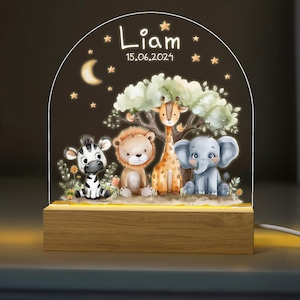 May include: A wooden night light with a clear acrylic insert featuring a whimsical jungle scene with a zebra, lion, giraffe, and elephant. The text "Liam 15.06.2021" is printed on the acrylic insert.