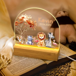 May include: A wooden base with a clear acrylic panel featuring a whimsical jungle scene with a tiger, hippopotamus, lion, zebra, and flamingos. The panel is illuminated with warm white LED lights. The text "Kevin 10.06.2024" is printed on the panel.