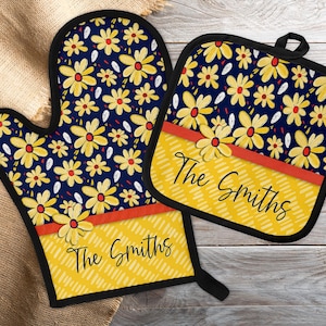 May include: A set of two yellow and blue oven mitts with a red stripe and the text "The Smiths" in black. The mitts feature a floral pattern.