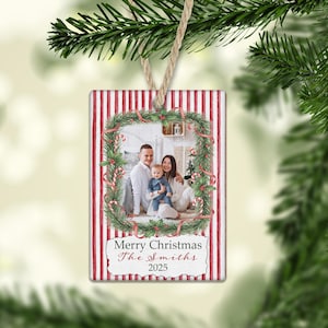May include: Rectangular Christmas ornament with a family photo, red and white striped background, and a green wreath. The ornament has the text "Merry Christmas The Smiths 2025" in a decorative font, and is suspended by a natural twine.