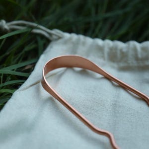 Eso World pure copper tongue scraper — traditional Ayurvedic oral care tool designed to remove buildup and support fresh breath naturally. Handcrafted from 100% pure copper for its antimicrobial and detoxifying properties. Durable, reusable, and fully recyclable alternative to plastic scrapers. Ideal for daily natural oral hygiene, zero-waste living, and holistic wellness routines. Part of Eso World’s premium eco-friendly essentials collection