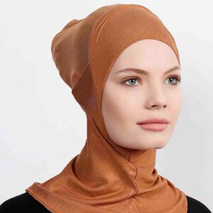May include: A brown jersey knit hijab with a turtleneck style. The hijab is made of a soft, stretchy fabric and has a close fit.