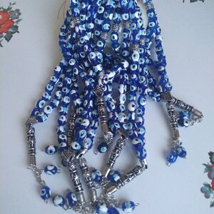 Peut inclure: Un ensemble de chapelets de pri&egrave;re en perles bleues et blanches avec des accents argent&eacute;s. Les perles sont enfil&eacute;es sur une cha&icirc;ne argent&eacute;e et ont un pompon &agrave; l'extr&eacute;mit&eacute;.