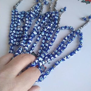 Peut inclure: Un ensemble de chapelets de pri&egrave;re en perles bleues et blanches avec des accents argent&eacute;s. Les perles sont enfil&eacute;es sur une cha&icirc;ne argent&eacute;e et ont un pompon &agrave; l'extr&eacute;mit&eacute;.