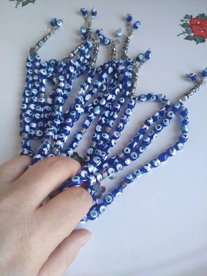 Peut inclure: Un ensemble de chapelets de pri&egrave;re en perles bleues et blanches avec des accents argent&eacute;s. Les perles sont enfil&eacute;es sur une cha&icirc;ne argent&eacute;e et ont un pompon &agrave; l'extr&eacute;mit&eacute;.
