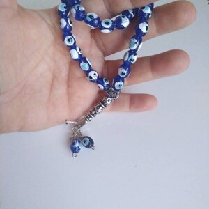Peut inclure: Un chapelet de pri&egrave;re bleu et blanc avec un charme argent&eacute; et deux charmes &oelig;il-de-dieu bleu et blanc qui pendent.