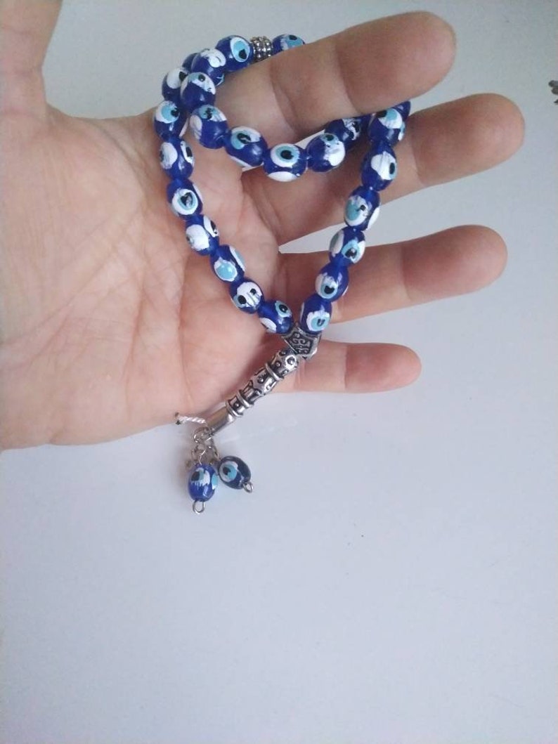 Peut inclure: Un chapelet de pri&egrave;re bleu et blanc avec un charme argent&eacute; et deux charmes &oelig;il-de-dieu bleu et blanc qui pendent.
