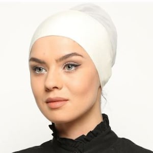 May include: A white cotton inner cap for women. The cap is made of a soft, stretchy fabric and is designed to be worn under a headscarf or hijab.