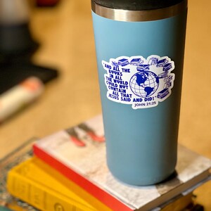 May include: A blue stainless steel travel mug with a sticker that says "And all the books in all the world could not contain all that Jesus said and did! John 21:25". The sticker features a globe surrounded by books.