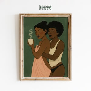 May include: Framed art print featuring two women embracing. One woman holds a cup of steaming coffee, wrapped in a pink towel. The other woman wears a white tank top and black underwear. The background is a dark green color, and the frame is a light wood color. The print is signed "FEMMAURA".
