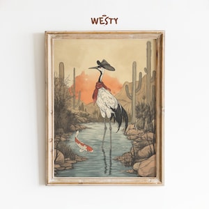 May include: Framed art print featuring a crane in a cowboy hat and red scarf standing in a river with a koi fish. The background depicts a desert landscape with cacti and mountains. The artwork has a vintage, illustrated style.