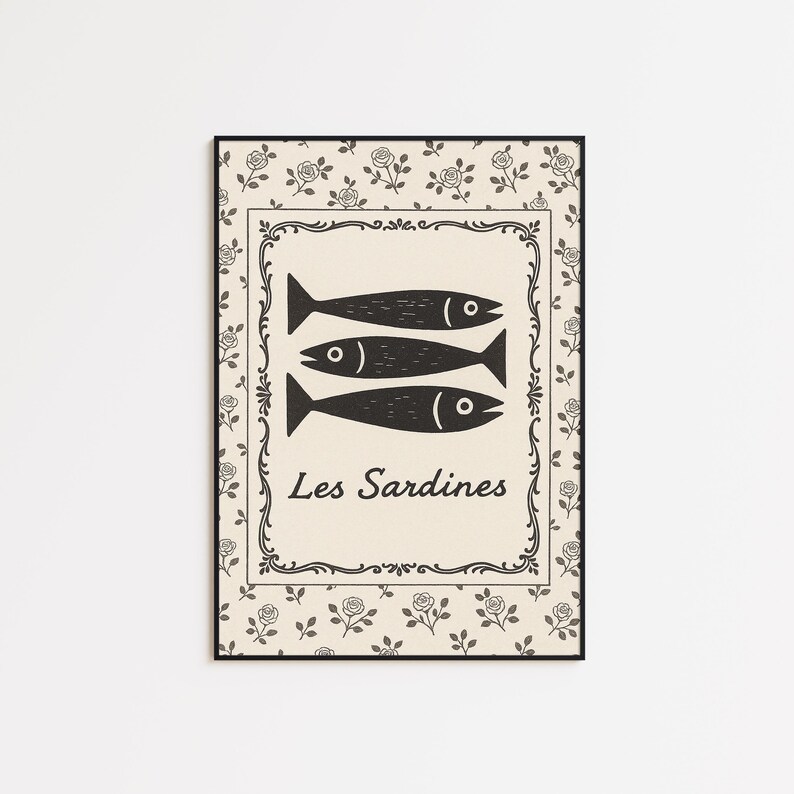 May include: Black framed art print featuring three stylized black fish above the words "Les Sardines". The artwork has a beige background with a decorative border and a floral pattern.