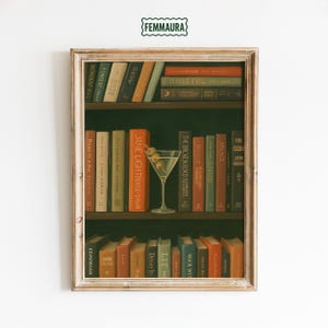 Op de afbeelding: Ingelijste print met een boekenplank, een martini glas en boeken in verschillende kleuren. De boeken hebben verschillende titels, wat een visueel interessante compositie creëert. De print heeft een vintage esthetiek.