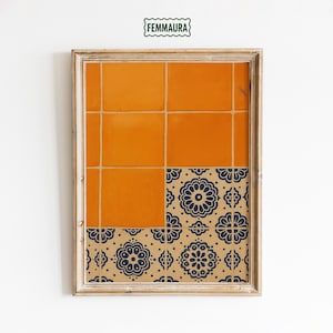 May include: Framed artwork featuring a geometric design. The top section displays orange tiles, while the bottom showcases a pattern of navy blue floral motifs on a tan background. The frame is a light wood color, and the artwork is against a white wall.