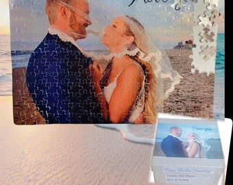 May include: A silver jigsaw puzzle with a photo of a couple on a beach. The puzzle is 500 pieces and measures 10 x 10 inches. The puzzle is in a box with the words "I love you" on it.