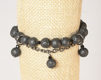 Puede incluir: Pulsera de cuentas de roca volcánica negra con una cadena plateada y tres colgantes de roca volcánica.