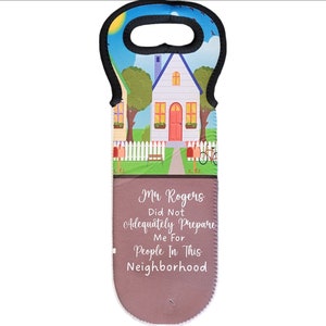May include: A brown and black neoprene wine bottle tote bag with a colorful illustration of a house with a white picket fence and a red door. The text "Mr. Rogers Did Not Adequately Prepare Me For People In This Neighborhood" is printed on the bag.