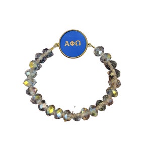 Op de afbeelding: Een blauwe en gouden armband met heldere kristallen kralen. De bedel heeft de Griekse letters "ΑΦΩ".