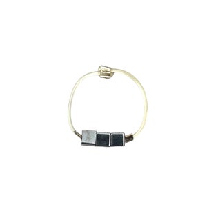 May include: A silver bracelet with three square-shaped charms on a clear elastic band.