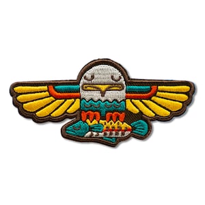 May include: Embroidered patch featuring a stylized eagle design with outstretched wings. The patch showcases a brown border, yellow wings, and a teal and orange body. The eagle is perched above a fish, with a detailed, colorful design.