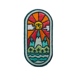 May include: Embroidered patch featuring a colorful landscape design. The patch depicts a smiling sun, mountains, trees, and water, all within an oval frame. The color palette includes orange, red, teal, and green, with a dark teal border.