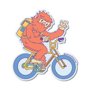 May include: A sticker featuring a cartoon Sasquatch riding a yellow bicycle with blue wheels. The orange-furred creature wears a yellow backpack and gives a peace sign. The sticker has a light blue border and the text "@starsandsequoias".