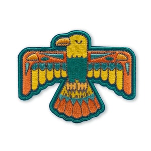 May include: Embroidered patch featuring a stylized eagle design. The patch has a teal border and features a yellow head, teal body, orange and yellow wings, and orange tail feathers. The eagle has a smiling expression.