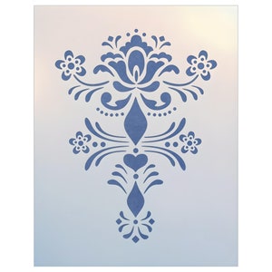 May include: A blue stencil featuring a symmetrical floral design. The design includes stylized flowers, hearts, and ornate scrollwork. The stencil is on a white background with a gradient effect, creating a soft, diffused look. Ideal for craft projects.