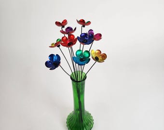 Könnte beinhalten: Ein Strauß bunter Metallblumen in einer grünen Vase. Die Blumen sind aus Aluminium und in einem Regenbogen von Farben bemalt.