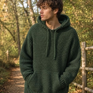 May include: A dark forest green long-sleeve hoodie crafted with a visible crochet stitch pattern. The garment features a hood with matching drawstrings, a large front kangaroo pocket, and ribbed knit cuffs and hemline for a structured fit.