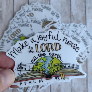 May include: White sticker with the text "Make a joyful noise to the LORD all the earth." The design includes an open book with musical notes, a globe, and the word "PSALM 98:4".