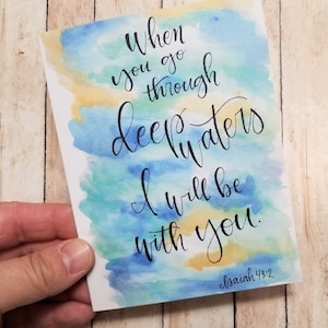 May include: Watercolor painting with a blue, green, and yellow background. The text reads "When you go through deep waters I will be with you. Isaiah 43:2".