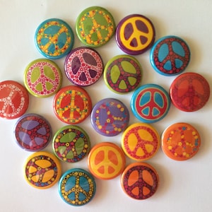 May include: A collection of 18 round peace sign buttons in various colors and patterns. The buttons feature a peace sign symbol in the center, surrounded by different designs, including flowers, dots, and swirls.