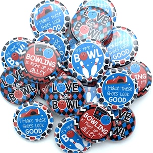 May include: A collection of round bowling-themed buttons. The buttons feature various designs, including bowling pins, bowling balls, and phrases like "Love to Bowl" and "Bowling is Right Up My Alley." The color scheme includes red, white, and blue.