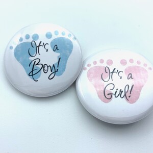 May include: Two round buttons with baby footprints. One button is blue with the text "It's a Boy!" and the other is pink with the text "It's a Girl!"
