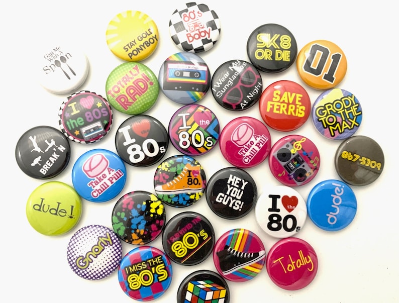 May include: A collection of 20 colorful 80s themed buttons with various designs and text, including "I love the 80s", "Totally Rad", "Gnarly", "Take a Chill Pill", "Save Ferris", "Break'n", "Dude", "867-5309", "Sk8 or Die", "Hey You Guys", "I Survived the 80s", "Stay Gold Ponyboy", "Wear My Sunglasses at Night", "I Miss the 80's", "Grody to the Max", "Totally", "I the 80s", "01", "Gnarly", "I the 80s".