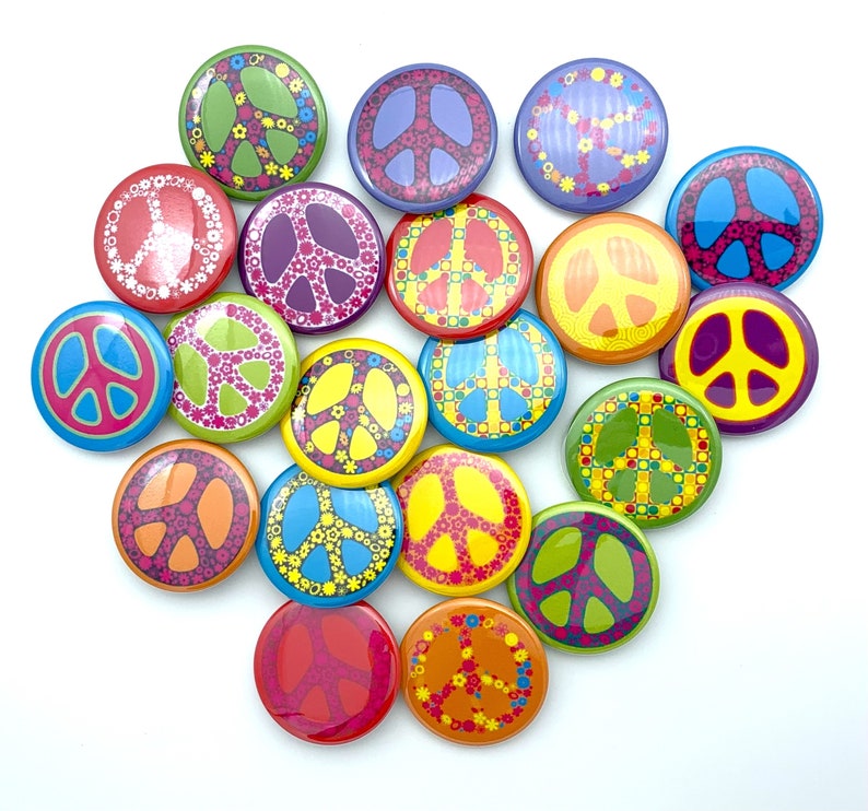 May include: A collection of 18 colorful peace sign buttons with various designs, including floral patterns, geometric shapes, and peace symbols. The buttons are arranged in a circle on a white background.
