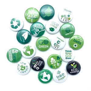 May include: A collection of 17 round green and white buttons with various eco-friendly messages and designs. The buttons feature phrases like "Go Green", "Eco Chick", "Tree Hugger", "Eco Warrior", and "Save the Planet".