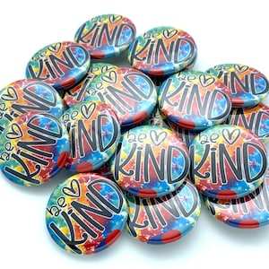 May include: A pile of colorful tie-dye buttons with the text "be kind" in black lettering. The buttons are all the same size and have a white background.