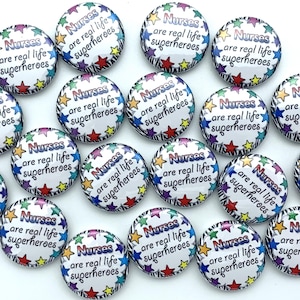 May include: A collection of 20 round buttons with a white background and a zebra print border. The buttons feature colorful stars and the text "Nurses are real life superheroes".