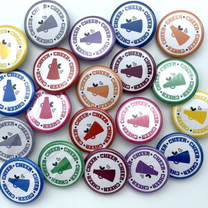May include: A collection of 20 round, colorful buttons with a white background and a graphic of a megaphone with a heart. The text "CHEER" is repeated around the edge of each button.