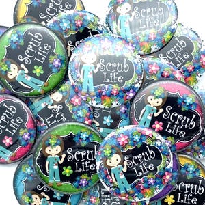 May include: A collection of colorful round buttons with a black and white design featuring a cartoon nurse with the text "Scrub Life".