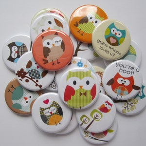May include: A collection of 14 round button pins featuring owls with various designs and colors. Some buttons have text, including "guess whoo loves u?" and "you're a hoot!"