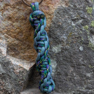 May include: A green, purple, and yellow braided rope keychain with a silver key ring.