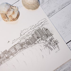 May include: A black and white pen and ink drawing of a city skyline with palm trees and a beach. The drawing is on a white piece of paper with a seashell on the top left corner.